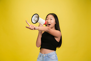 Image showing Portrait of young asian girl isolated on yellow studio background