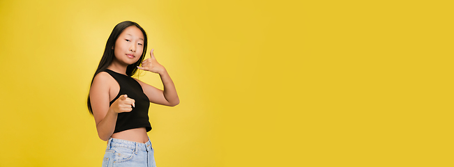 Image showing Portrait of young asian girl isolated on yellow studio background