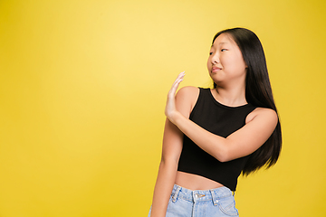 Image showing Portrait of young asian girl isolated on yellow studio background