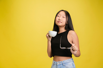 Image showing Portrait of young asian girl isolated on yellow studio background