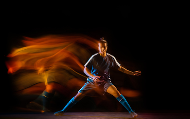 Image showing Football or soccer player on black background in mixed light, fire shadows