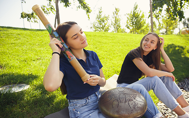 Image showing Two girls, friends playing music at summer\'s city street