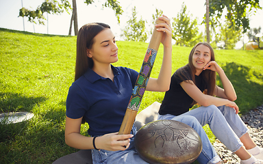 Image showing Two girls, friends playing music at summer\'s city street