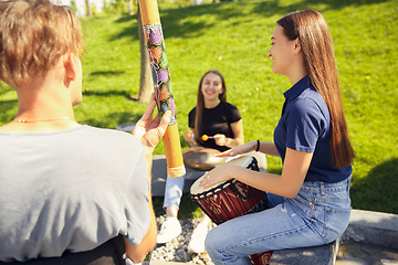 Image showing Happy handicapped man on a wheelchair spending time with friends playing live instrumental music outdoors