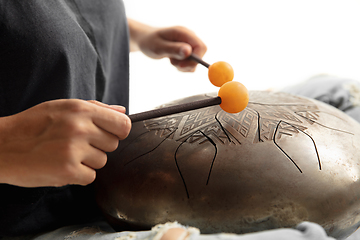 Image showing A close up of hands playing the hank drum on white studio background