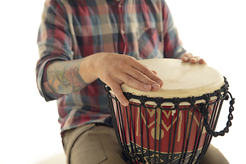 Image showing Man plays ethnic drum darbuka percussion, close up musician isolated on white studio background