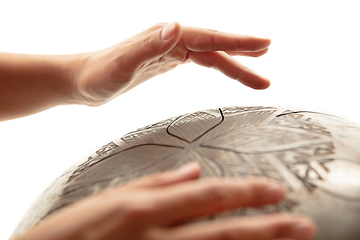 Image showing A close up of hands playing the hank drum on white studio background