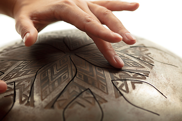 Image showing A close up of hands playing the hank drum on white studio background