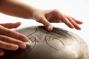 Image showing A close up of hands playing the hank drum on white studio background