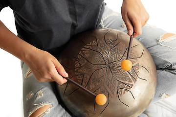 Image showing A close up of hands playing the hank drum on white studio background