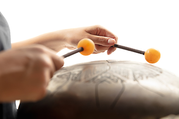 Image showing A close up of hands playing the hank drum on white studio background