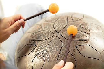 Image showing A close up of hands playing the hank drum on white studio background