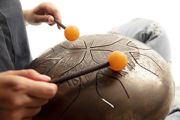 Image showing A close up of hands playing the hank drum on white studio background