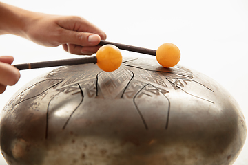 Image showing A close up of hands playing the hank drum on white studio background