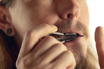 Image showing Man plays Jew\'s harp. Action. Close-up of man playing vibrating instrument for meditation. Ancient Asian musical instrument