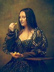 Image showing Young woman as Mona Lisa on dark background. Retro style, comparison of eras concept.