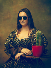 Image showing Young woman as Mona Lisa on dark background. Retro style, comparison of eras concept.