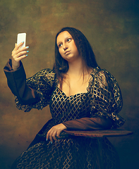 Image showing Young woman as Mona Lisa on dark background. Retro style, comparison of eras concept.