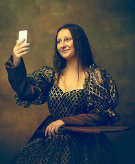 Image showing Young woman as Mona Lisa on dark background. Retro style, comparison of eras concept.