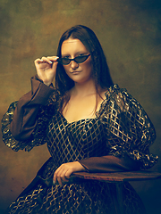 Image showing Young woman as Mona Lisa on dark background. Retro style, comparison of eras concept.