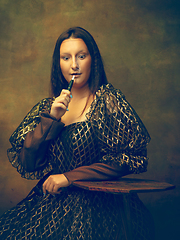 Image showing Young woman as Mona Lisa on dark background. Retro style, comparison of eras concept.