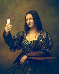 Image showing Young woman as Mona Lisa on dark background. Retro style, comparison of eras concept.