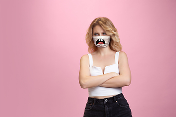 Image showing Portrait of young girl with emotion on her protective face mask isolated on studio background. Beautiful female model, funny expression