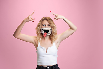 Image showing Portrait of young girl with emotion on her protective face mask isolated on studio background. Beautiful female model, funny expression