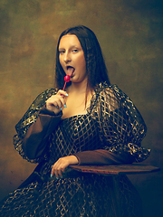 Image showing Young woman as Mona Lisa on dark background. Retro style, comparison of eras concept.