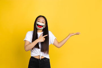 Image showing Portrait of young girl with emotion on her protective face mask isolated on studio background. Beautiful female model, funny expression