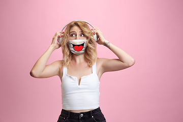 Image showing Portrait of young girl with emotion on her protective face mask isolated on studio background. Beautiful female model, funny expression