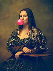 Image showing Young woman as Mona Lisa on dark background. Retro style, comparison of eras concept.