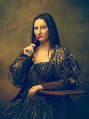 Image showing Young woman as Mona Lisa on dark background. Retro style, comparison of eras concept.