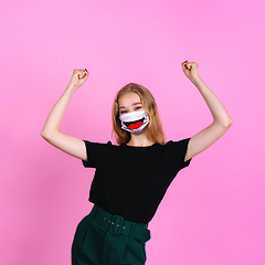 Image showing Portrait of young girl with emotion on her protective face mask isolated on studio background. Beautiful female model, funny expression