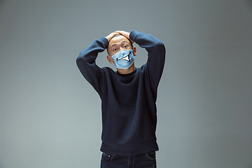 Image showing Portrait of young man with emotion on his protective face mask isolated on studio background. Beautiful male model, funny expression