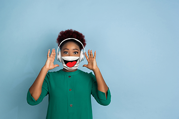 Image showing Portrait of young girl with emotion on her protective face mask isolated on studio background. Beautiful female model, funny expression