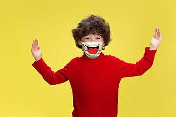 Image showing Portrait of little boy with emotion on his protective face mask isolated on studio background. Beautiful male model, funny expression