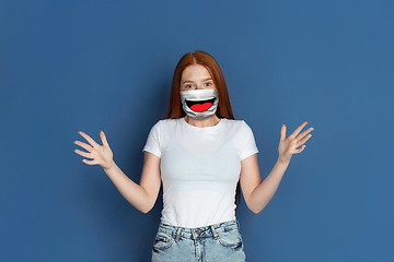 Image showing Portrait of young girl with emotion on her protective face mask isolated on studio background. Beautiful female model, funny expression