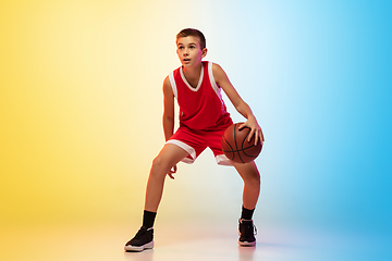 Image showing Full length portrait of a young basketball player with ball on gradient background