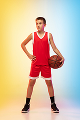 Image showing Full length portrait of a young basketball player with ball on gradient background