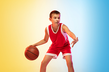 Image showing Full length portrait of a young basketball player with ball on gradient background