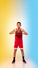 Image showing Full length portrait of a young basketball player with ball on gradient background