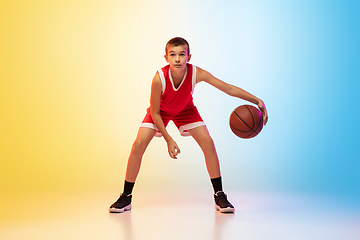 Image showing Full length portrait of a young basketball player with ball on gradient background