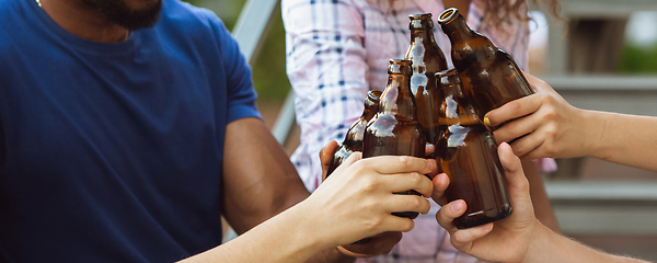 Image showing Hands of young friends, colleagues during beer drinking, having fun, laughting and celebrating together. Flyer with copyspace