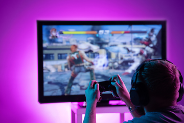 Image showing Back view shot of professional gamer playing online video game on his personal computer.