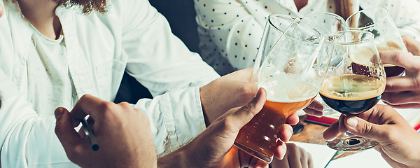 Image showing Hands of young friends, colleagues during beer drinking, having fun, laughting and celebrating together. Flyer with copyspace