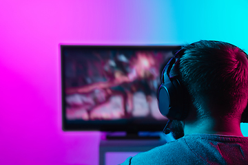 Image showing Back view shot of professional gamer playing online video game on his personal computer.