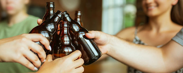 Image showing Hands of young friends, colleagues during beer drinking, having fun, laughting and celebrating together. Flyer with copyspace