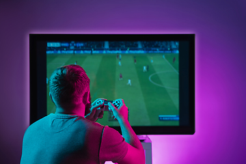 Image showing Back view shot of professional gamer playing online video game on his personal computer.