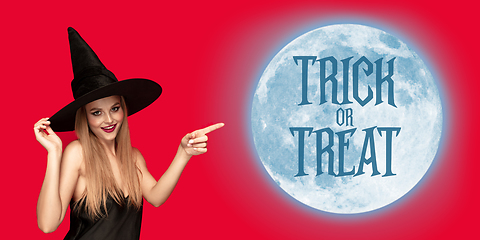 Image showing Young woman in hat as a witch on scary red background